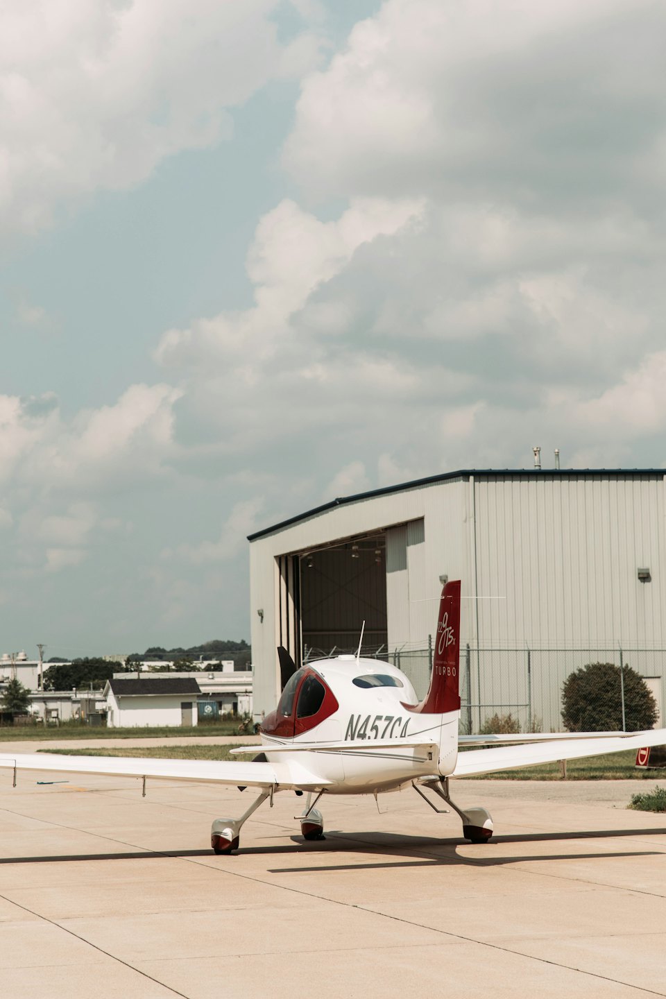 A sleek private jet is parked on a tarmac outside a hangar.