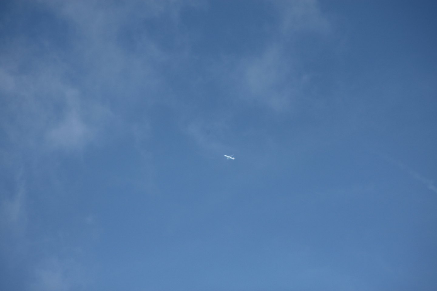 A small airplane flies across a clear blue sky.